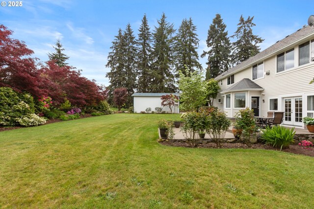 view of green lawn featuring french doors and a patio