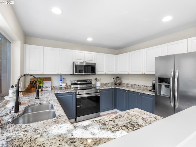 kitchen with light stone countertops, a sink, stainless steel appliances, recessed lighting, and white cabinetry