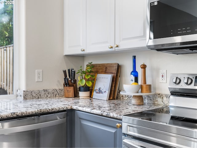 kitchen with white cabinetry, light stone countertops, and stainless steel appliances