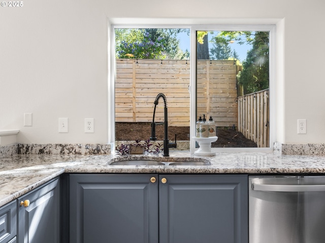 interior space with stainless steel dishwasher, a sink, and light stone countertops