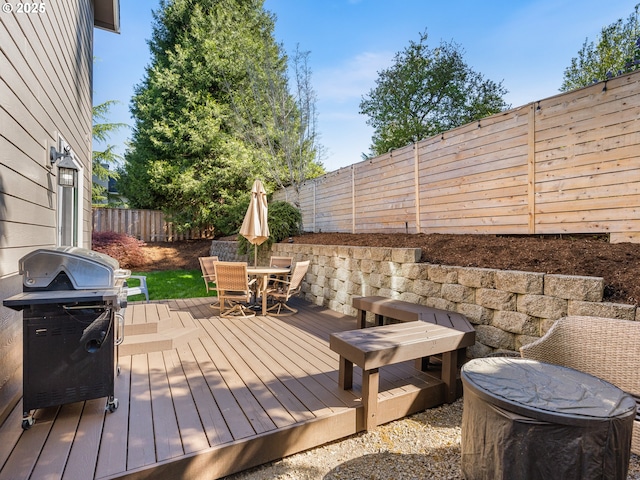 deck with area for grilling, outdoor dining space, and a fenced backyard