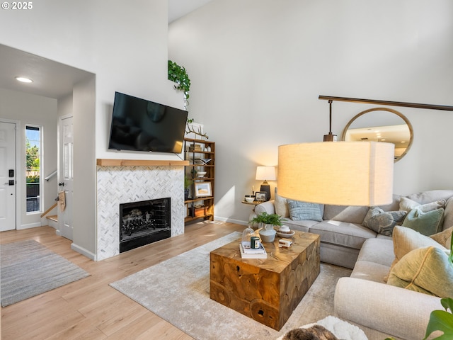 living area featuring baseboards, a high ceiling, a fireplace, and wood finished floors