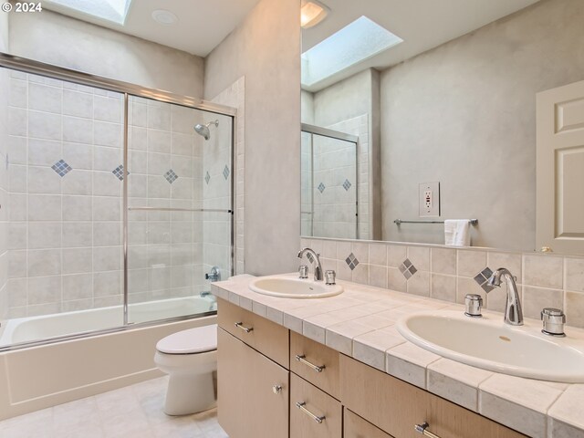 9112 NW Wiley Ln, Portland, OR 97229 - bathroom with a skylight, toilet, double vanity, bath / shower combo with glass door, and tile patterned floors