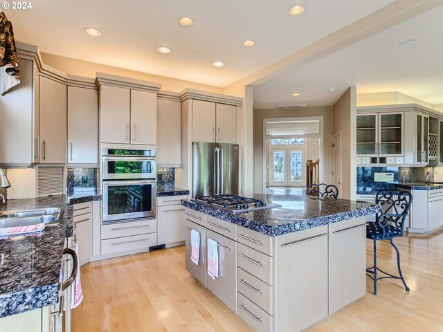 9112 NW Wiley Ln, Portland, OR 97229 - kitchen featuring appliances with stainless steel finishes, a sink, a center island, decorative backsplash, and light wood finished floors