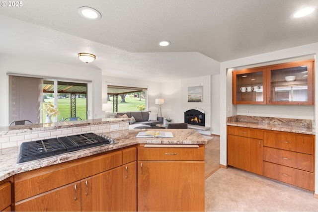 kitchen with glass insert cabinets, a large fireplace, open floor plan, stainless steel gas stovetop, and recessed lighting