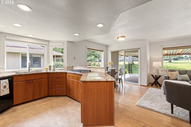 kitchen featuring a sink, brown cabinets, a peninsula, and a textured ceiling