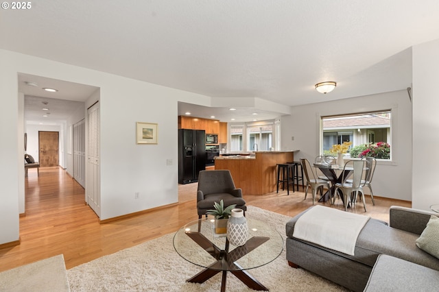 living room with light wood-style floors, recessed lighting, and baseboards