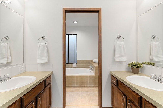 bathroom with a sink, recessed lighting, a bath, and two vanities