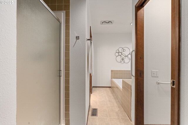 bathroom with tile patterned flooring, a shower with door, a garden tub, and visible vents