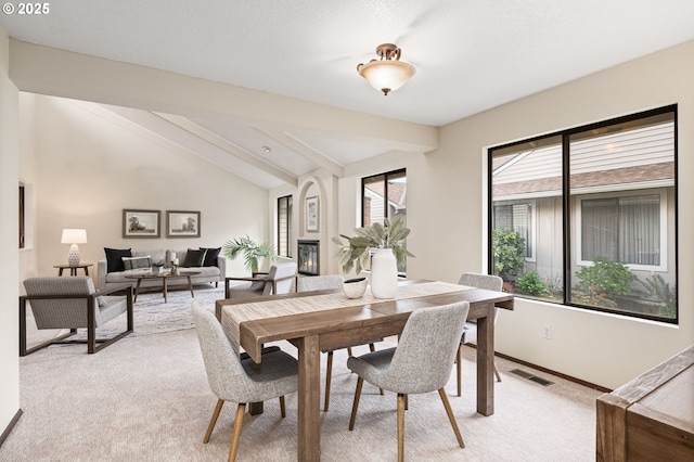 dining room featuring visible vents, vaulted ceiling with beams, baseboards, and light carpet
