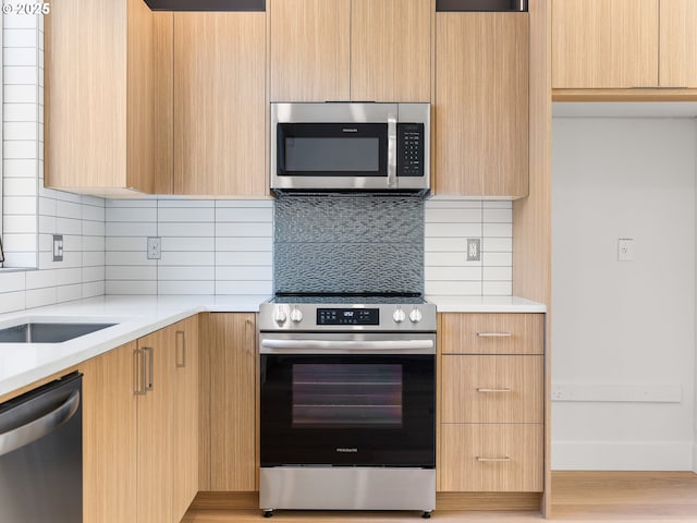 kitchen featuring appliances with stainless steel finishes, light brown cabinets, tasteful backsplash, and light hardwood / wood-style floors