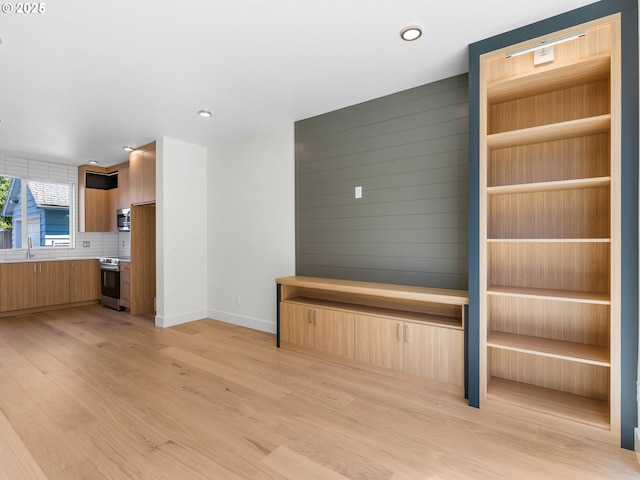 unfurnished living room featuring sink and light wood-type flooring