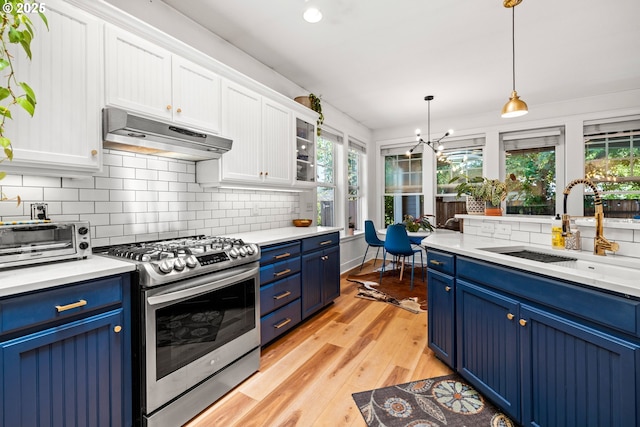 9628 N Exeter Ave, Portland, OR 97203 - kitchen with stainless steel range with gas stovetop, blue cabinets, under cabinet range hood, and white cabinets