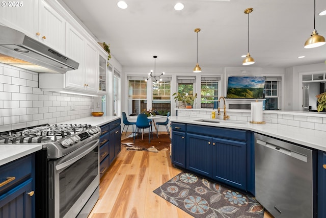 9628 N Exeter Ave, Portland, OR 97203 - kitchen featuring appliances with stainless steel finishes, blue cabinetry, under cabinet range hood, decorative backsplash, and recessed lighting
