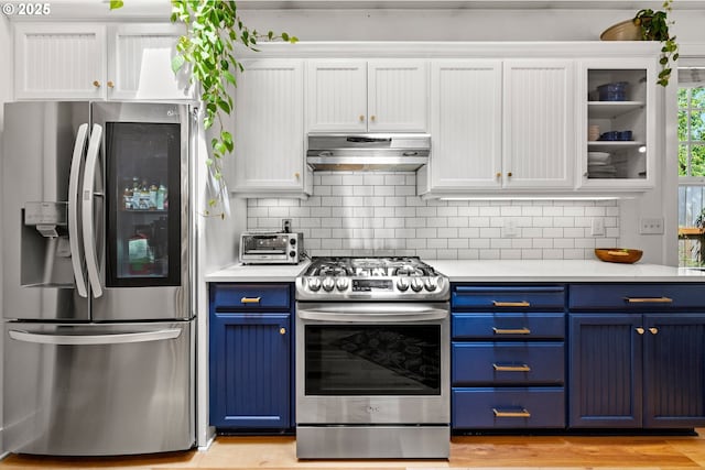 9628 N Exeter Ave, Portland, OR 97203 - kitchen with stainless steel appliances, blue cabinets, under cabinet range hood, light countertops, and white cabinetry
