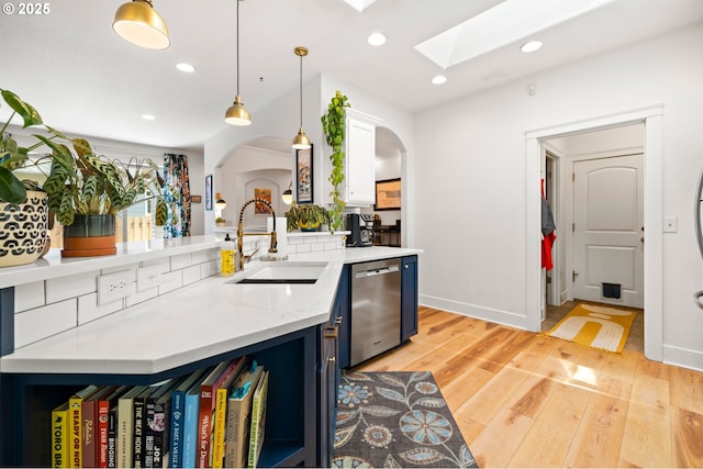 9628 N Exeter Ave, Portland, OR 97203 - kitchen featuring stainless steel dishwasher, arched walkways, a skylight, decorative light fixtures, and light wood-type flooring