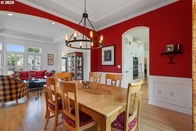 10440 SW 141st Ave, Beaverton, OR 97008 - dining room featuring arched walkways, a raised ceiling, light wood-style flooring, ornamental molding, and a wainscoted wall