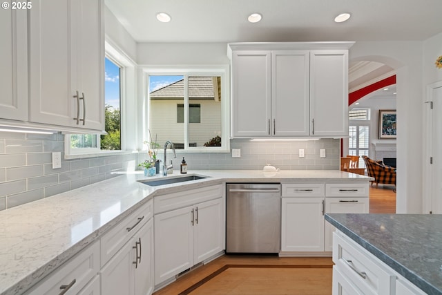 10440 SW 141st Ave, Beaverton, OR 97008 - kitchen featuring stainless steel dishwasher, arched walkways, white cabinets, light wood-style floors, and decorative backsplash
