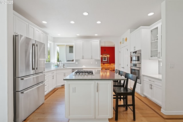 10440 SW 141st Ave, Beaverton, OR 97008 - kitchen with stainless steel appliances, a breakfast bar, backsplash, white cabinetry, and light wood finished floors