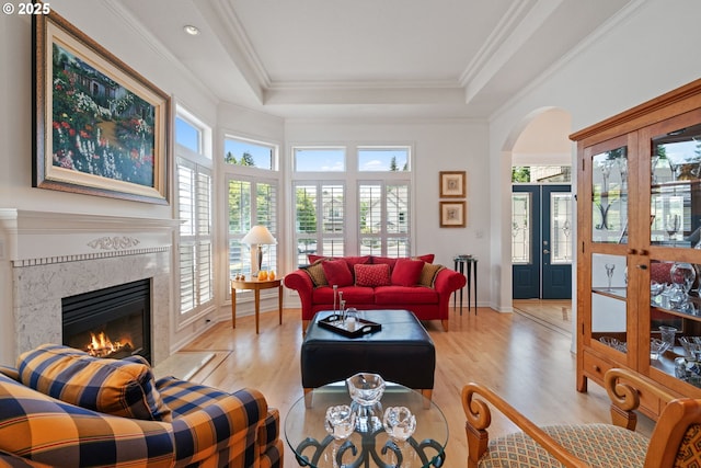 10440 SW 141st Ave, Beaverton, OR 97008 - living room with arched walkways, wood finished floors, a fireplace, a tray ceiling, and crown molding