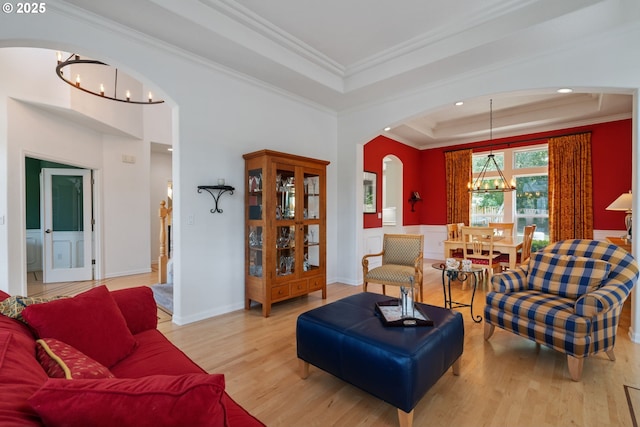 10440 SW 141st Ave, Beaverton, OR 97008 - living room featuring a chandelier, arched walkways, a raised ceiling, crown molding, and light wood-style flooring