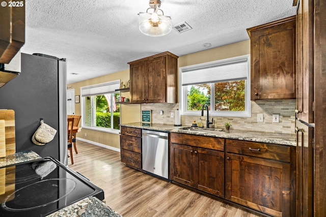 1561 Balboa St, Eugene, OR 97408 - kitchen featuring stainless steel appliances, light wood-type flooring, tasteful backsplash, a textured ceiling, and light stone counters