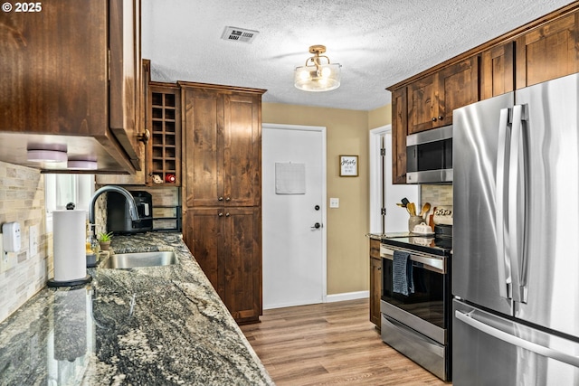 1561 Balboa St, Eugene, OR 97408 - kitchen with stainless steel appliances, decorative backsplash, light wood-type flooring, dark stone counters, and a textured ceiling