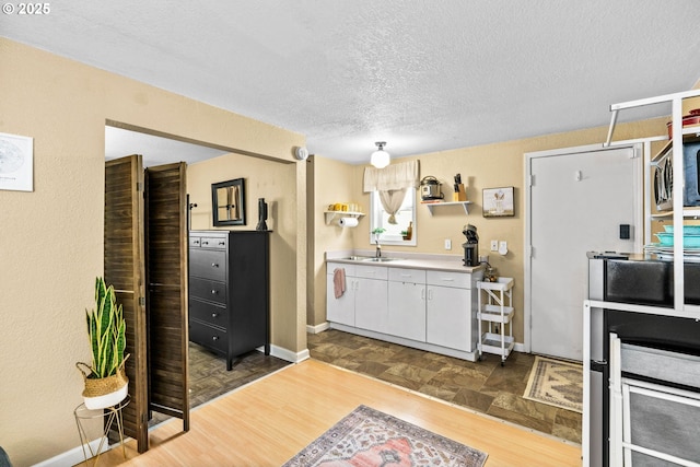 1561 Balboa St, Eugene, OR 97408 - kitchen featuring a textured ceiling, white cabinets, wood finished floors, and light countertops