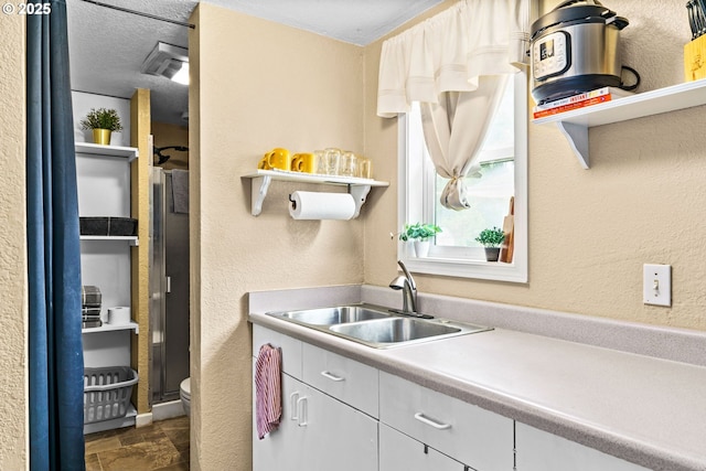 1561 Balboa St, Eugene, OR 97408 - kitchen featuring open shelves, a textured wall, white cabinets, light countertops, and dark stone finish floors