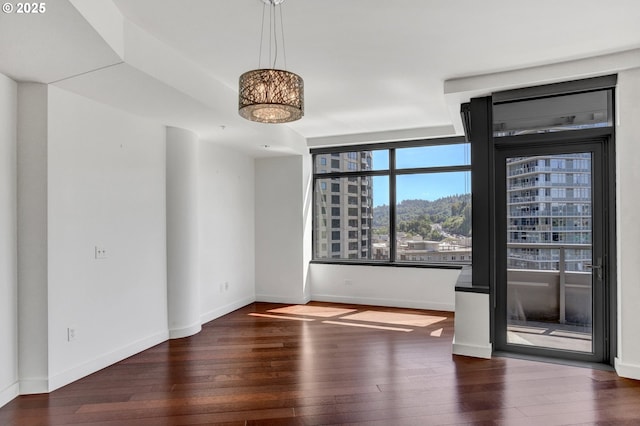 unfurnished room with baseboards and wood-type flooring