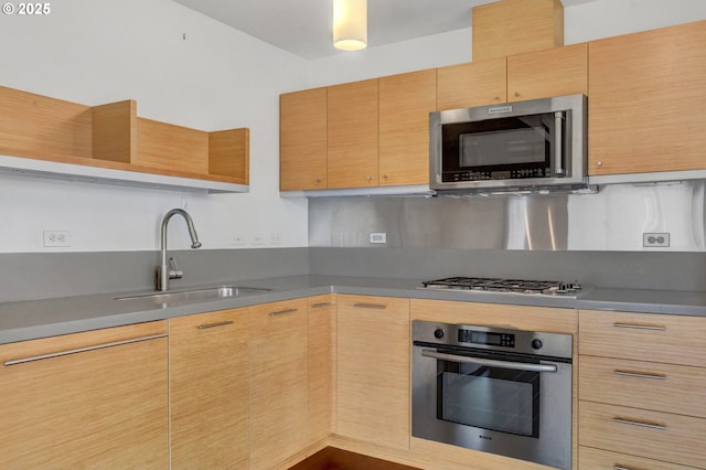 kitchen featuring stainless steel appliances, decorative backsplash, a sink, and light brown cabinets