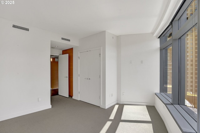 carpeted empty room featuring baseboards and visible vents