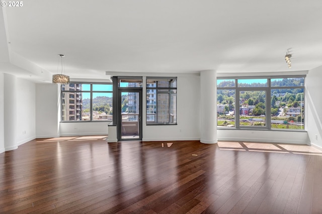 unfurnished living room featuring wood-type flooring, baseboards, and a chandelier