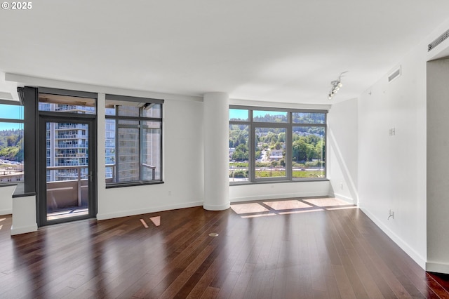 unfurnished room featuring visible vents, baseboards, a healthy amount of sunlight, and hardwood / wood-style floors