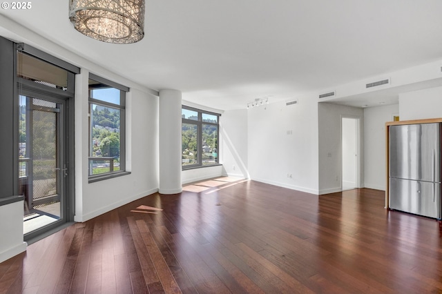 unfurnished living room featuring visible vents, baseboards, wood finished floors, and a chandelier