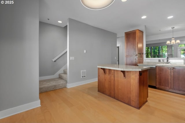 1919 NE 50th Way, Hillsboro, OR 97124 - kitchen featuring a sink, light wood finished floors, a breakfast bar area, stainless steel dishwasher, and light countertops