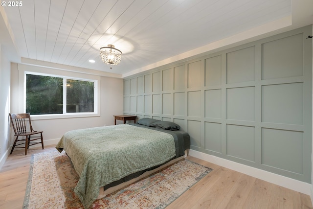 bedroom featuring an inviting chandelier, wood ceiling, and light hardwood / wood-style flooring