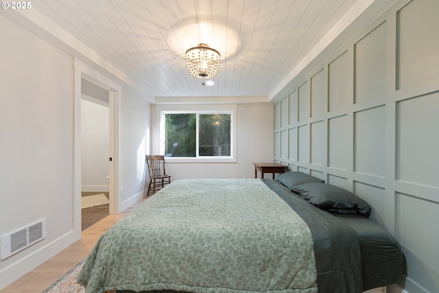 bedroom with light hardwood / wood-style flooring, wood ceiling, and a notable chandelier