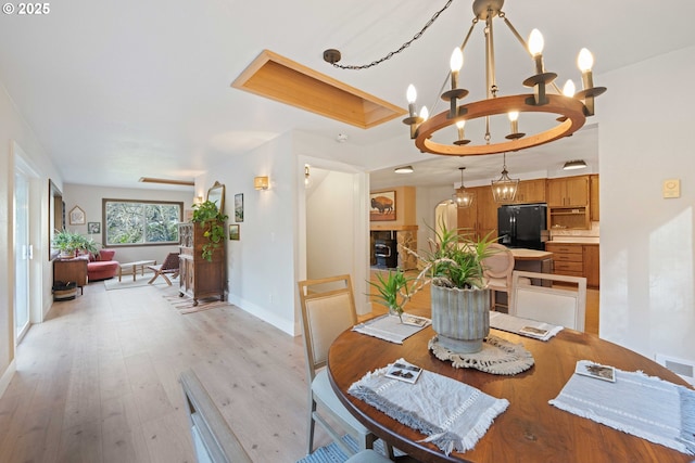 dining room featuring a raised ceiling, light wood-type flooring, and a chandelier