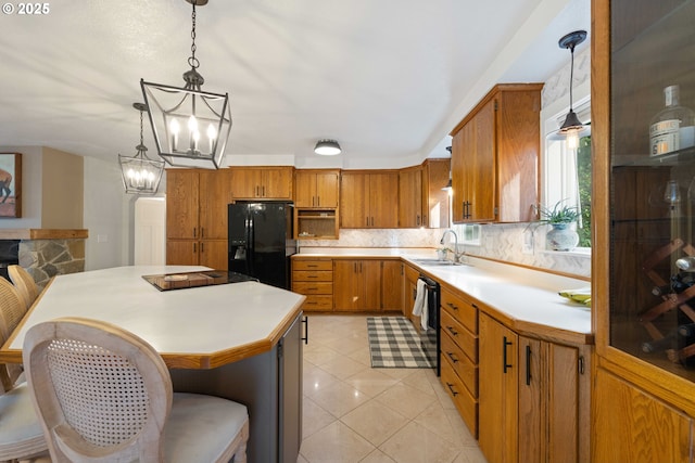 kitchen with sink, a notable chandelier, decorative light fixtures, a kitchen island, and black appliances