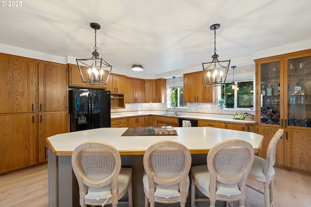 kitchen with tasteful backsplash, black appliances, decorative light fixtures, an inviting chandelier, and a kitchen island