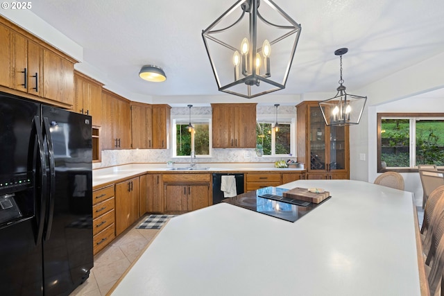 kitchen featuring decorative backsplash, black appliances, pendant lighting, light tile patterned floors, and an inviting chandelier