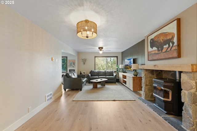 living room featuring wood-type flooring, a wood stove, and ceiling fan