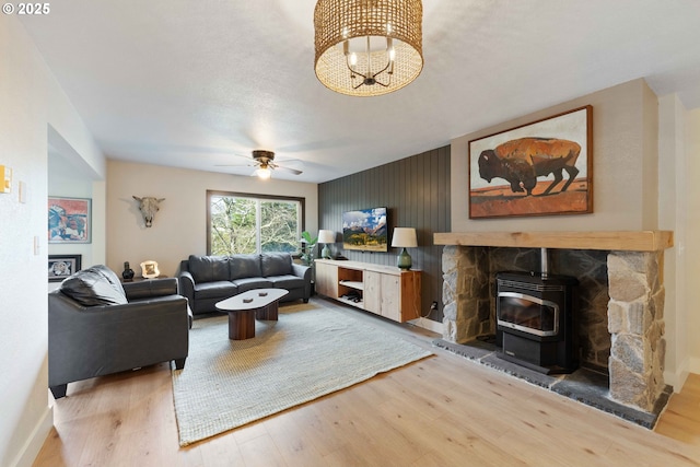 living room with ceiling fan, wood-type flooring, and a wood stove