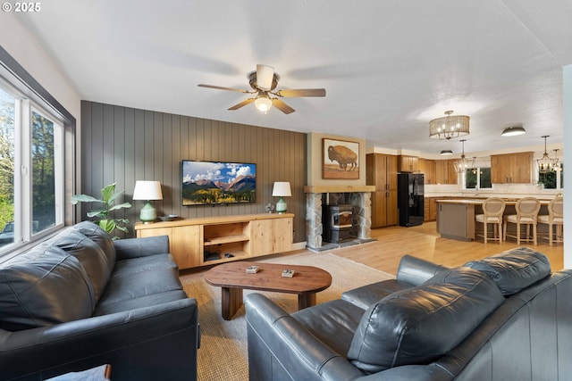 living room featuring ceiling fan with notable chandelier, light hardwood / wood-style floors, and a wood stove