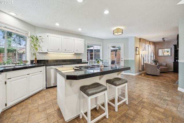19580 SW 56th Ct, Tualatin, OR 97062 - kitchen with appliances with stainless steel finishes, stone tile flooring, a kitchen bar, white cabinetry, and recessed lighting