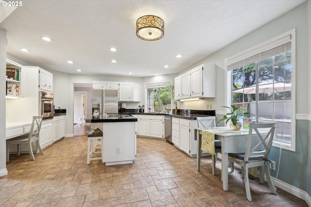 19580 SW 56th Ct, Tualatin, OR 97062 - kitchen with appliances with stainless steel finishes, white cabinets, a center island, dark countertops, and recessed lighting