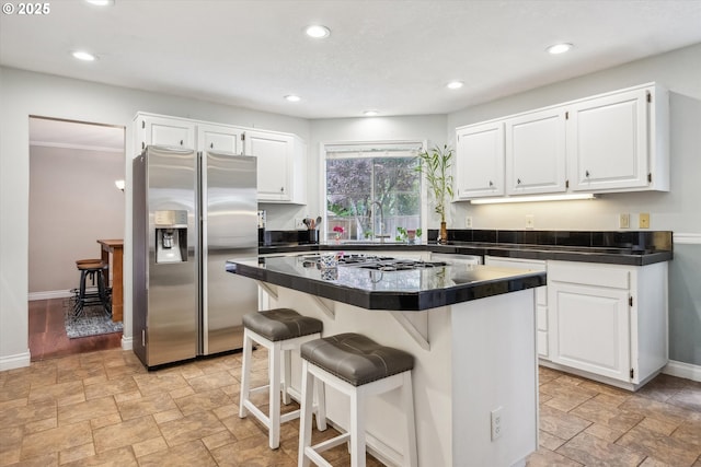 19580 SW 56th Ct, Tualatin, OR 97062 - kitchen with appliances with stainless steel finishes, dark countertops, stone finish floors, white cabinets, and a kitchen breakfast bar
