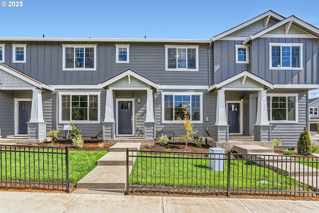 view of front of property featuring a fenced front yard, board and batten siding, and a front lawn