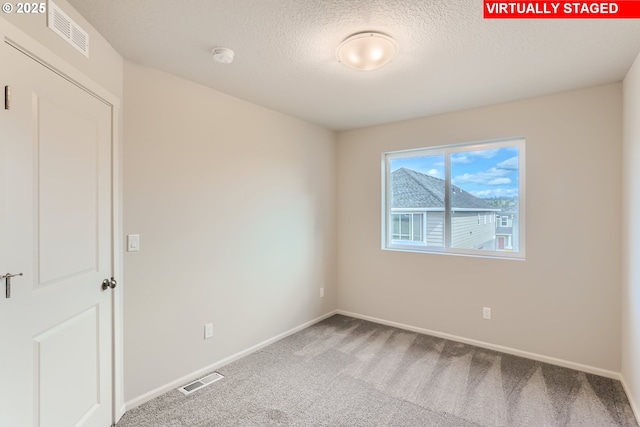 spare room with baseboards, visible vents, carpet floors, and a textured ceiling